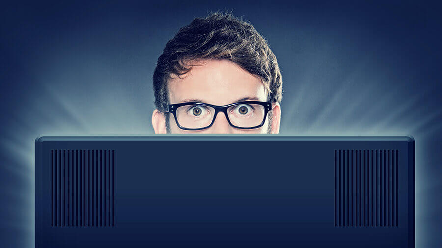 man peeking over computer screen