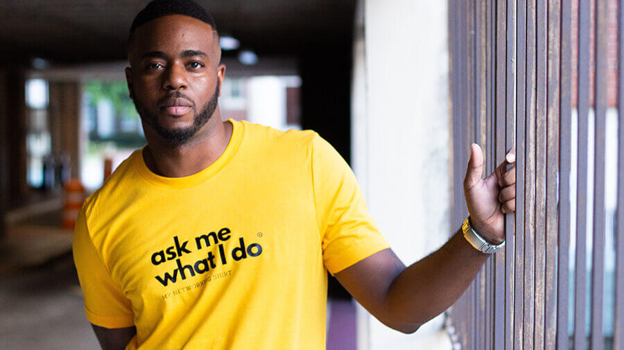 Man wearing yellow t-shirt saying ask me what I do