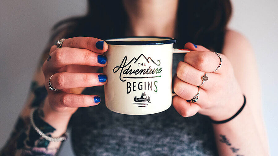 Woman holding coffee mug that says adventure begins