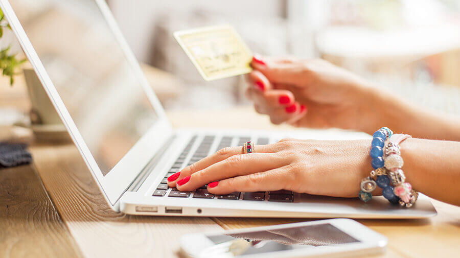 woman holding credit card at a computer