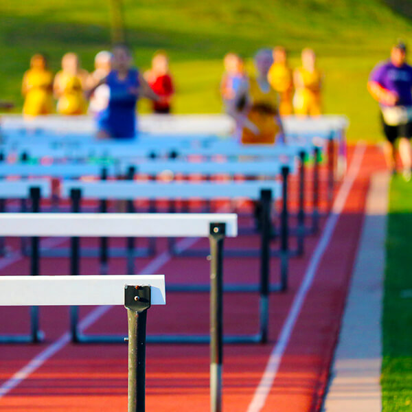 Runners jumping over hurdles that represent freelance business challenges