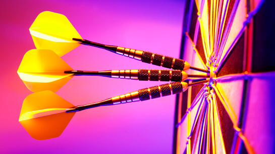 Darts in the bullseye of a target to represent coaching to an achievement