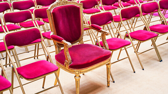 Concept of how a branding expert can elevate a brand. Shown by one ornate throne among rows of plain folding chairs