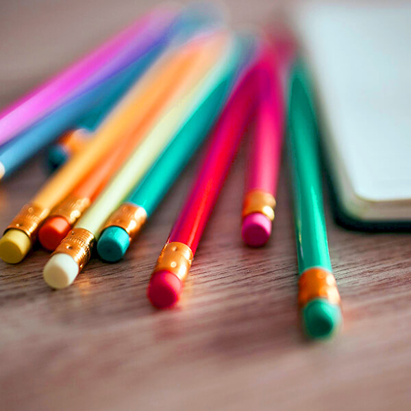Colorful pencils next to a notebook ready for writing freelance business tips