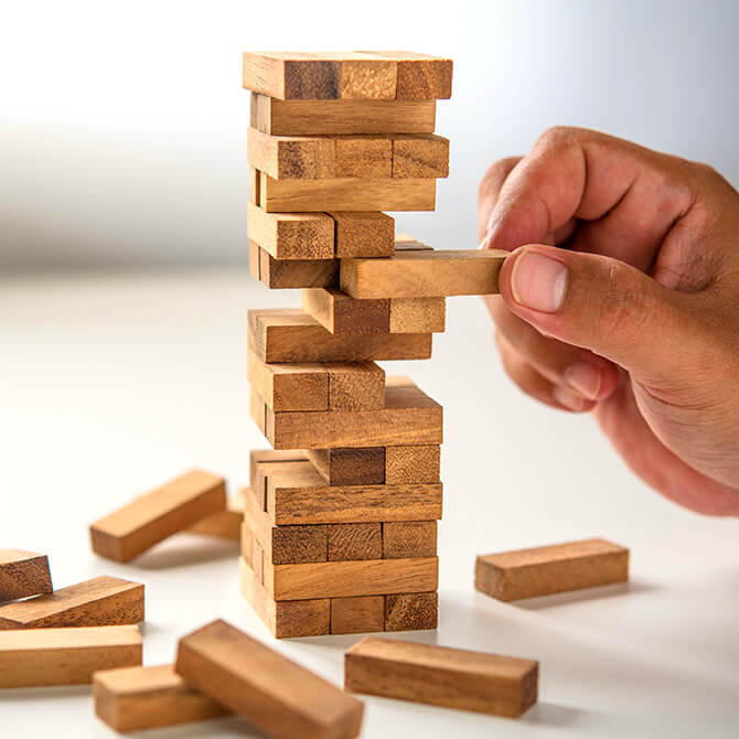 Man playing Jenga and taking a risk by pulling out a wooden block, similar to taking a risk on a bad pricing strategy