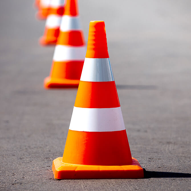 Bright orange and white construction cones blocking the road to represent freelancer pricing roadblocks