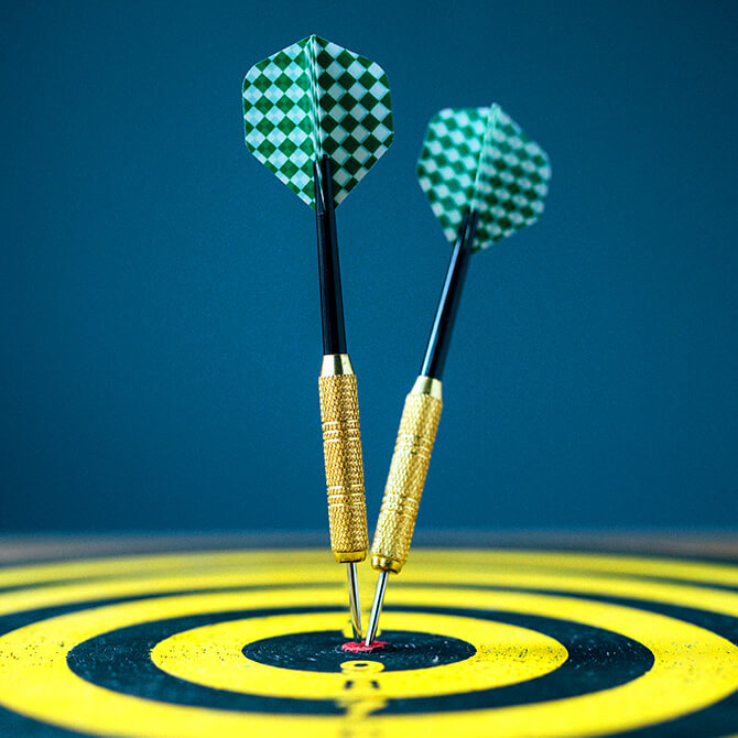 Two teal checkered darts in the center of a black and yellow bullseye to represent getting your freelance pricing right