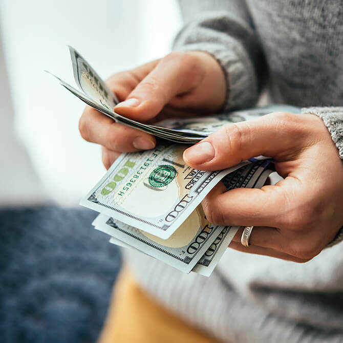 Hundred dollar bills in a freelancer's hand after getting paid their full rate