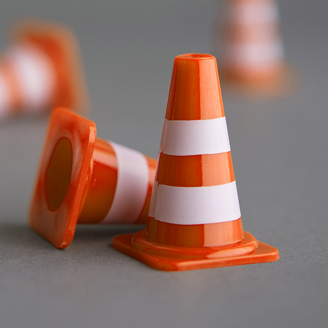 Two orange traffic cones, one standing, one tipped over on its side, reminding people to use caution and do their due diligence before they buy