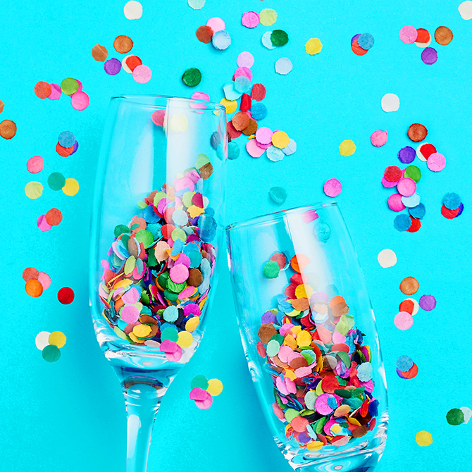 Two champagne flutes full of paper confetti, in a bright turquoise background, with confetti sprinkled around the glasses to celebrate fit for the Client Conflict Cure