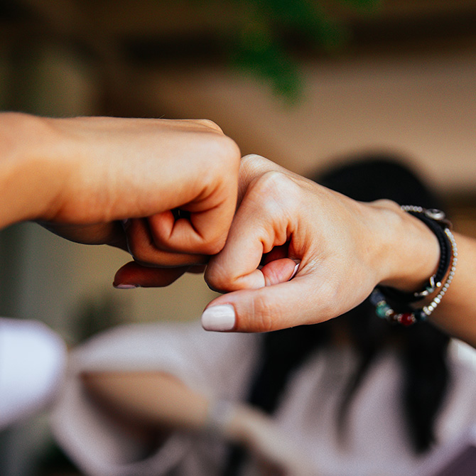A fist bump between two women business owners — a service provider and client