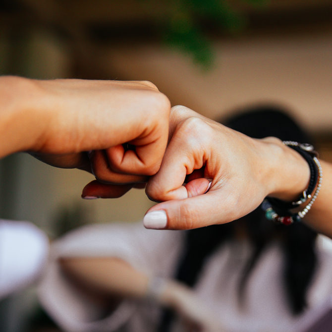 A fist bump between a client and their service partner