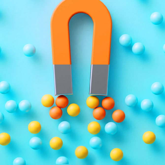 An strong brand represented by an orange magnet pulling orange and yellow balls (ideal clients) toward it in a sea of aqua balls on an aqua background